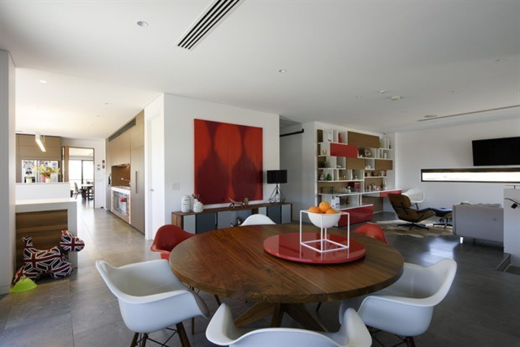Modern dining room with a wooden table, white chairs, and a large red artwork.