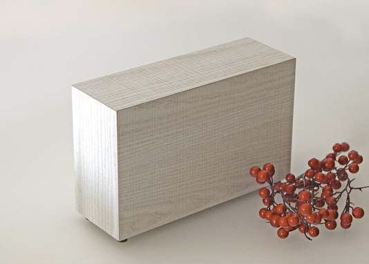 Urna cineraria in legno posta accanto a un mazzo di bacche rosse su un tavolo.