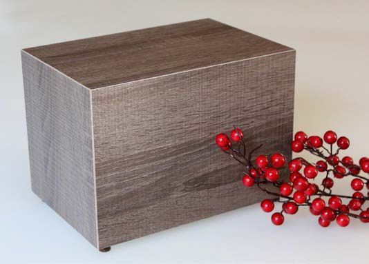 Urna cineraria in legno è posta accanto a un mazzo di bacche rosse.