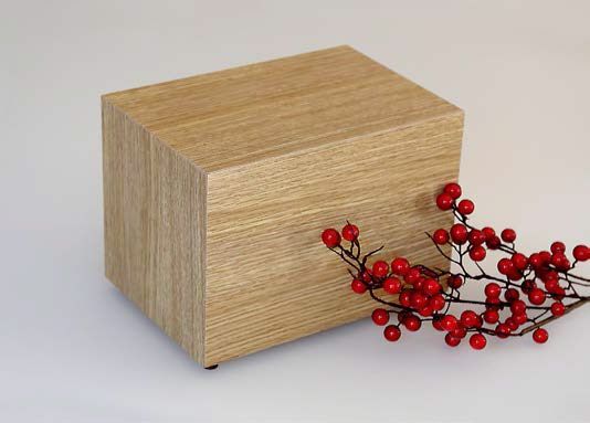 Urna cineraria in legno con delle bacche rosse sopra.