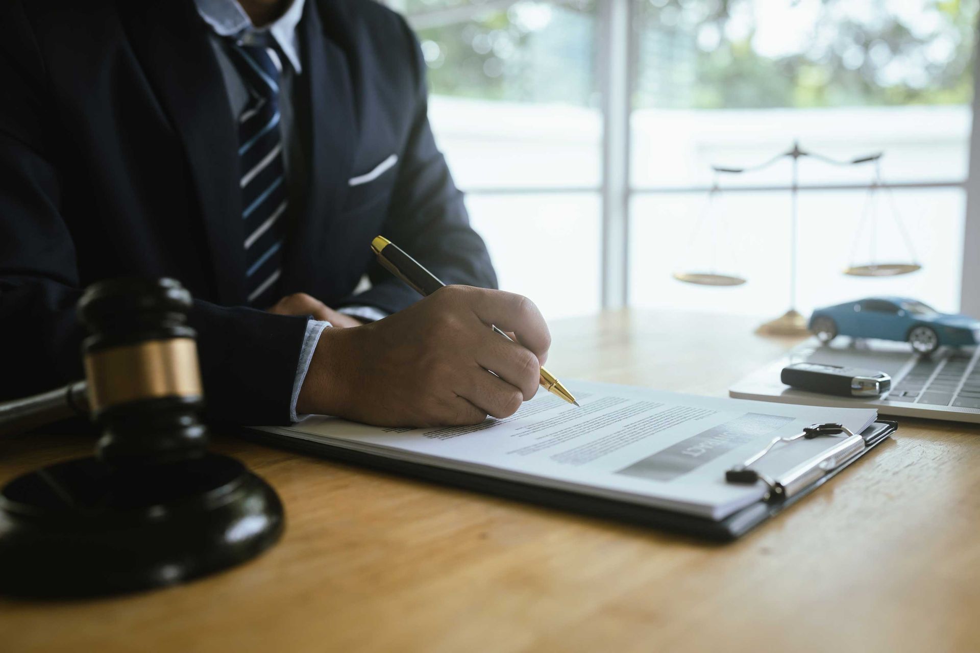 A lawyer in a suit signs legal documents with pen.