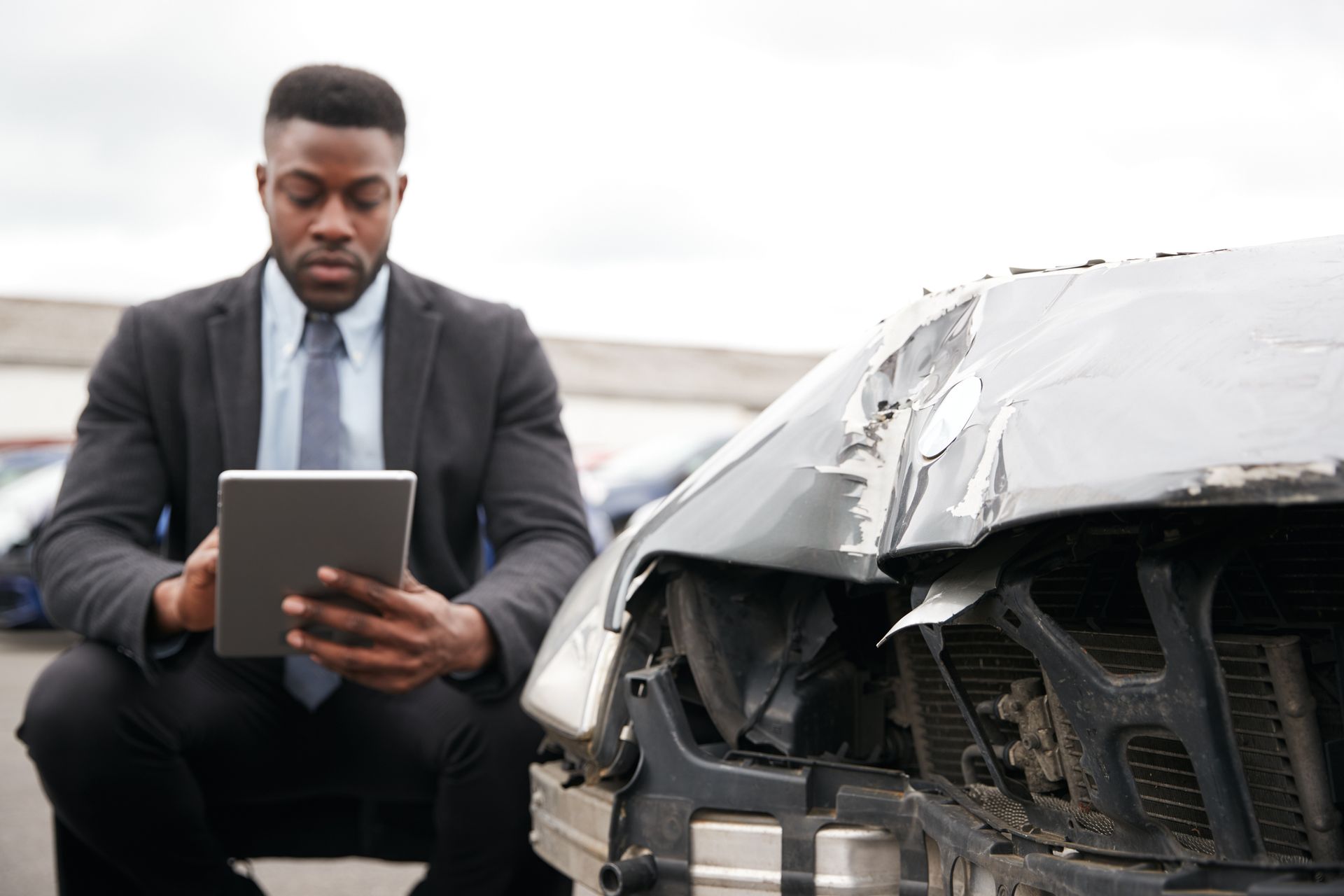 A lawyer inspecting damage to a car from a truck accident.