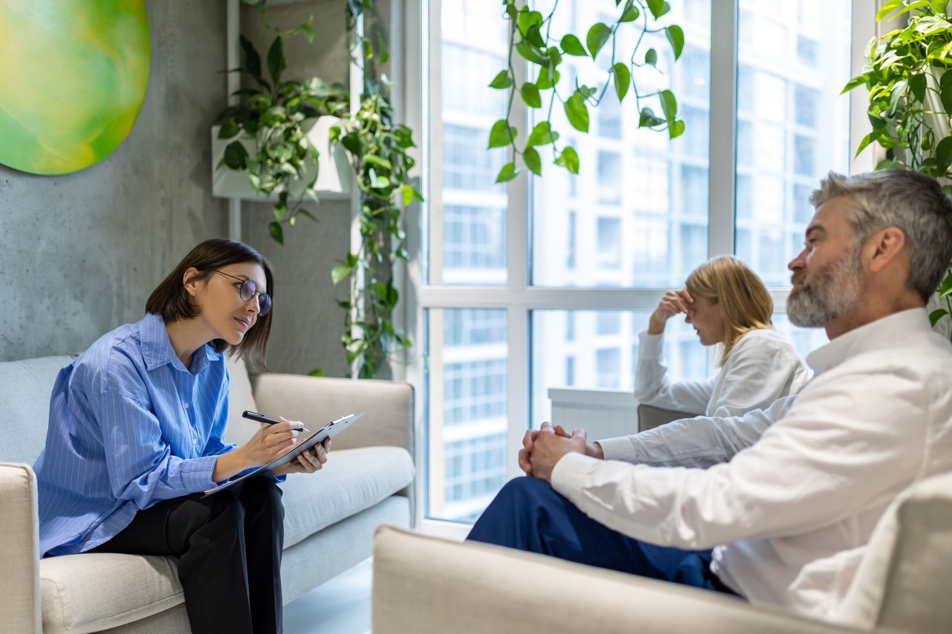 A woman is sitting on a couch talking to a man and woman.