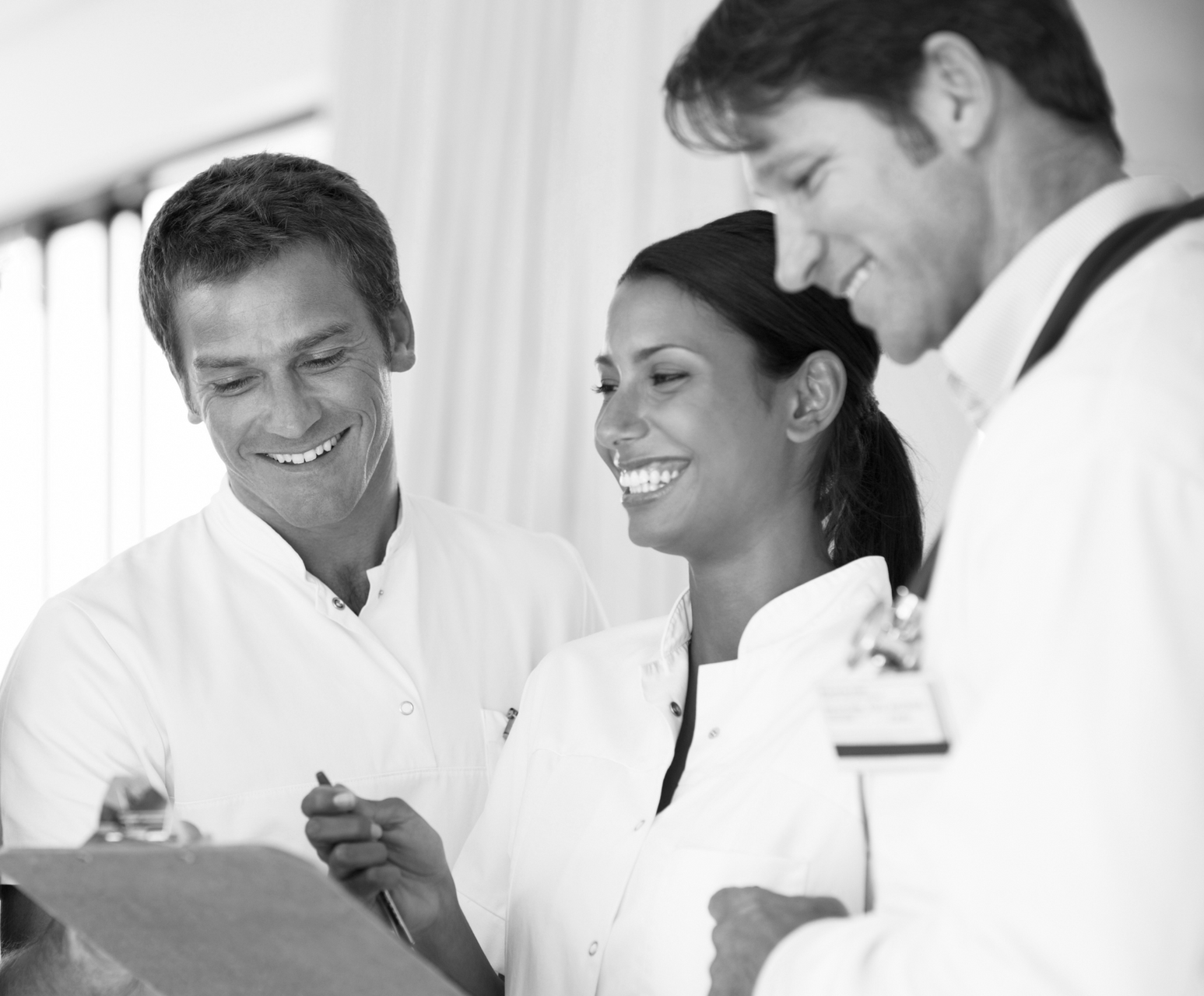 A black and white photo of three doctors looking at a clipboard