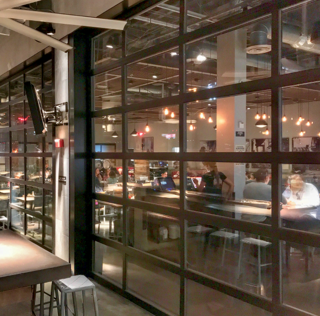 A restaurant with a lot of windows and people sitting at tables