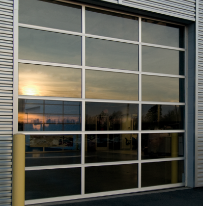 Glass garage door reflecting a sunset. Silver frame, industrial building.