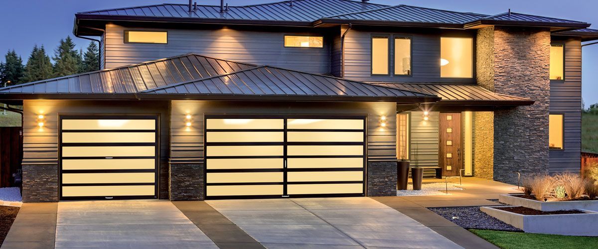 A large house with a large garage door is lit up at night.