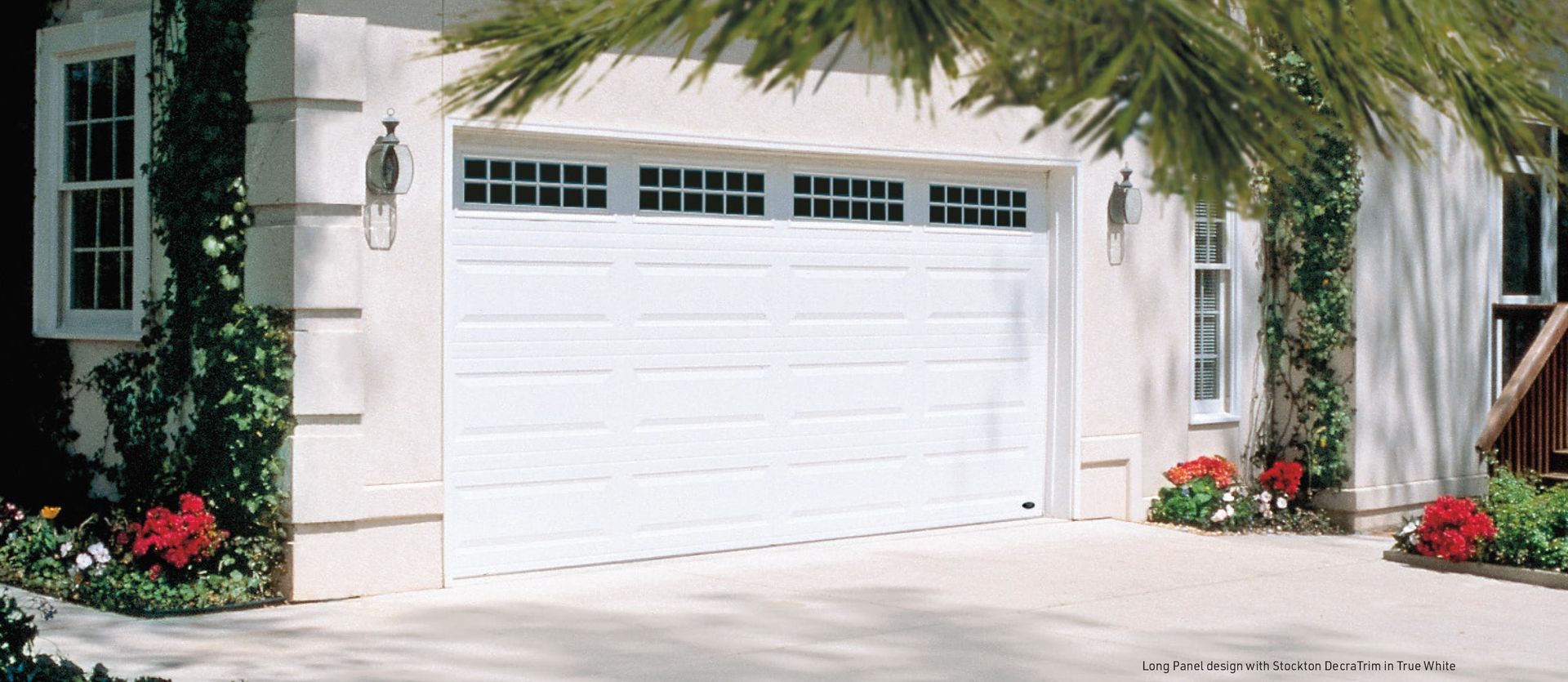 A white garage door is sitting in front of a white house