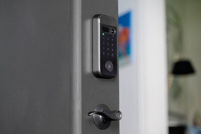 A modern, dark-gray smart door lock with a touchscreen keypad and a small lever handle mounted on a door.