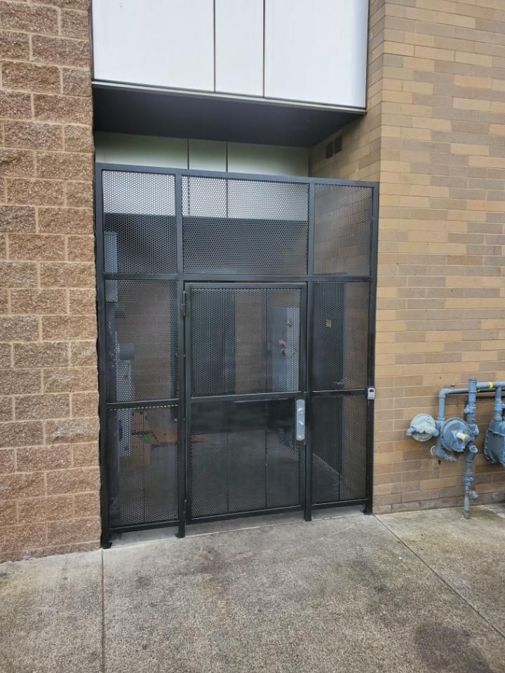 Black metal security gate on a brick building with a concrete floor, gas meter visible.