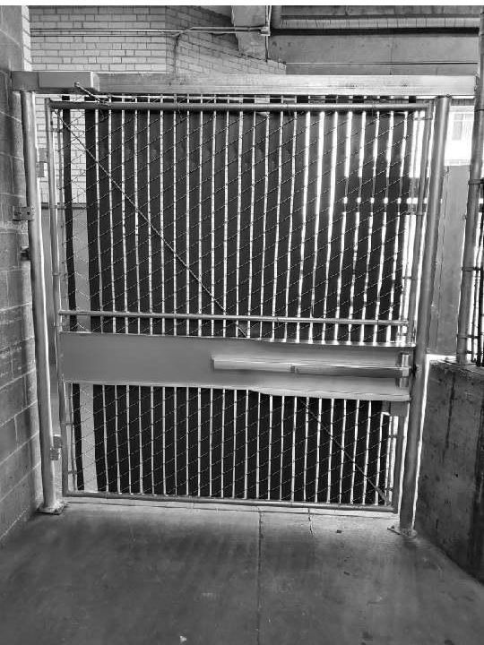Metal gate with vertical bars, in a concrete building.