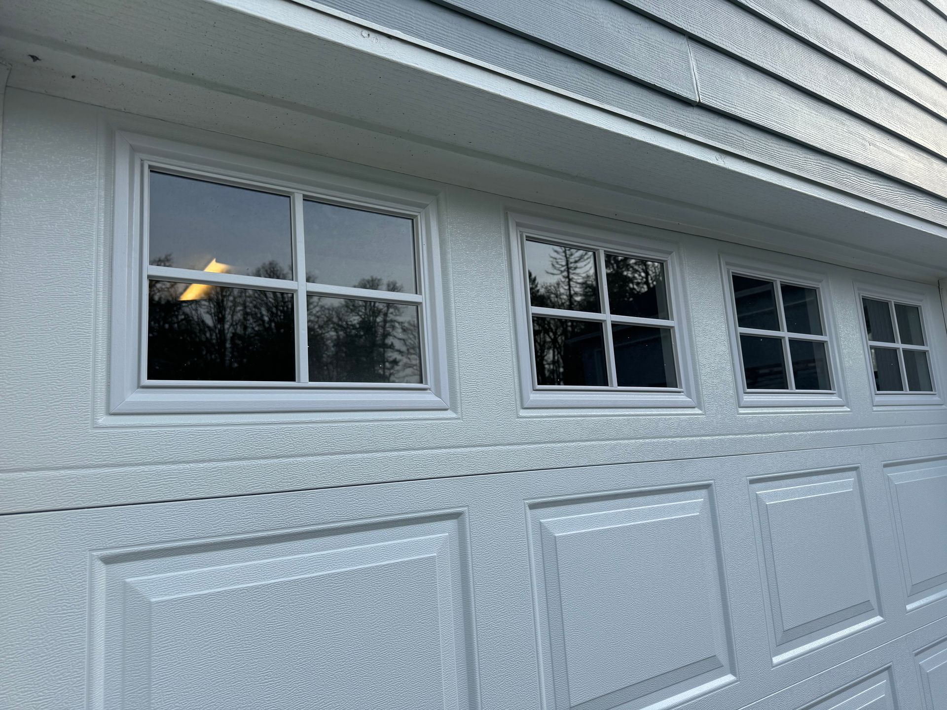 White garage door with four small, square windows across the top.