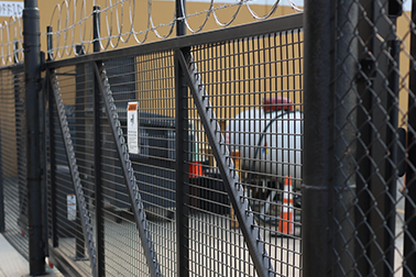 A fence with barbed wire on it is surrounding a building.