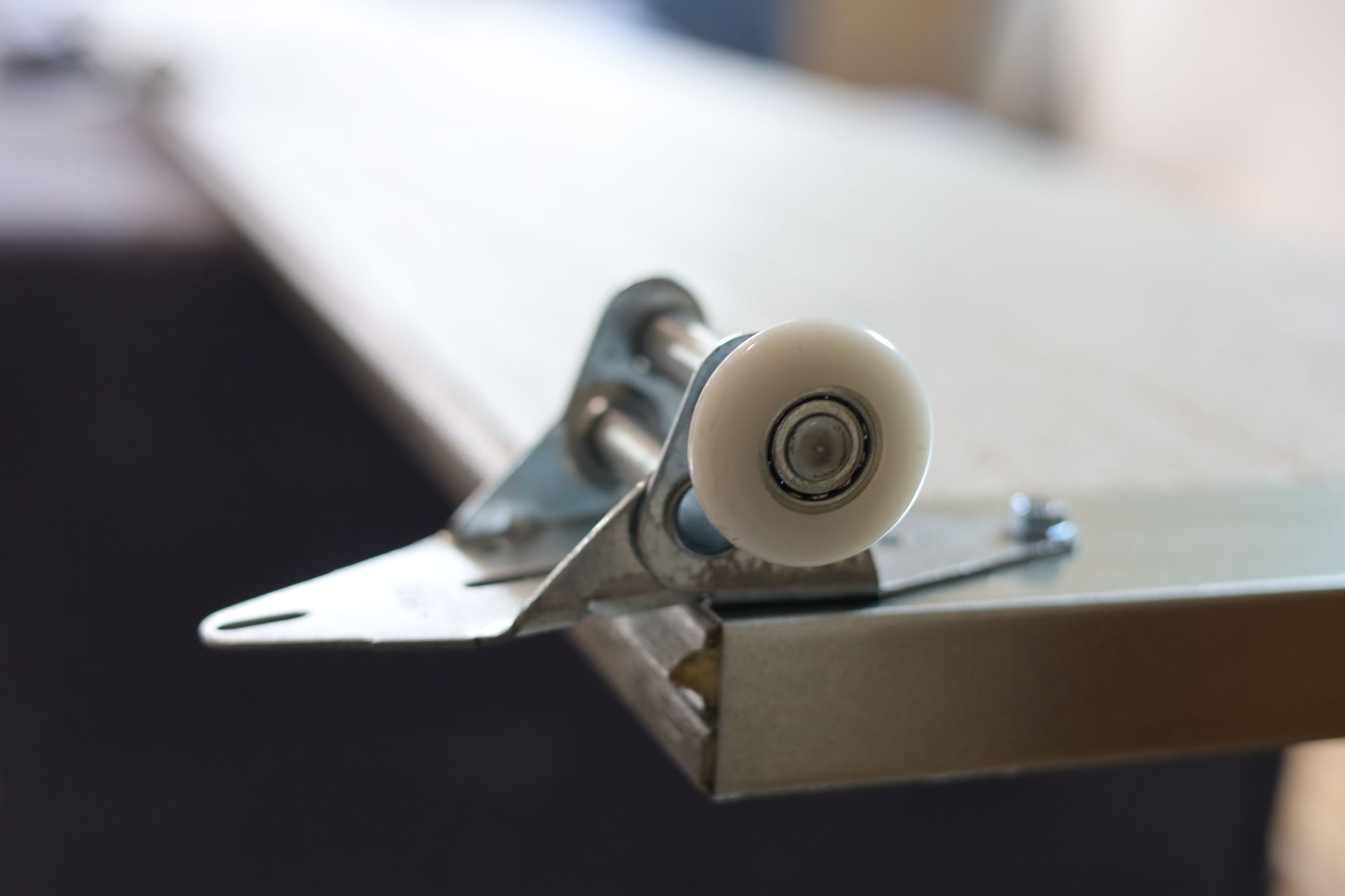 Garage door roller mounted on a metal panel, close up.
