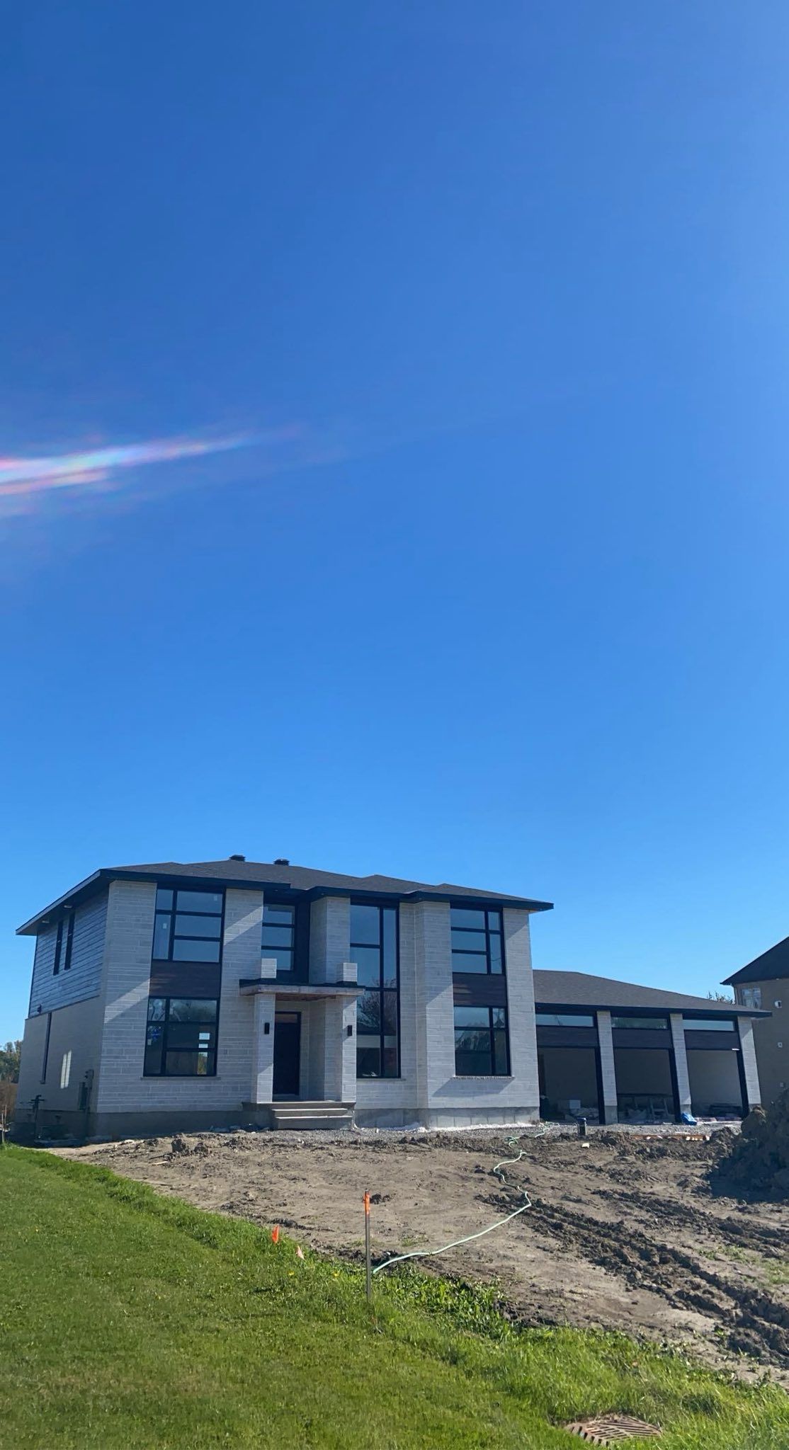 Maison neuve à deux étages en construction, par une belle journée ensoleillée. Ciel bleu, façade blanche.
