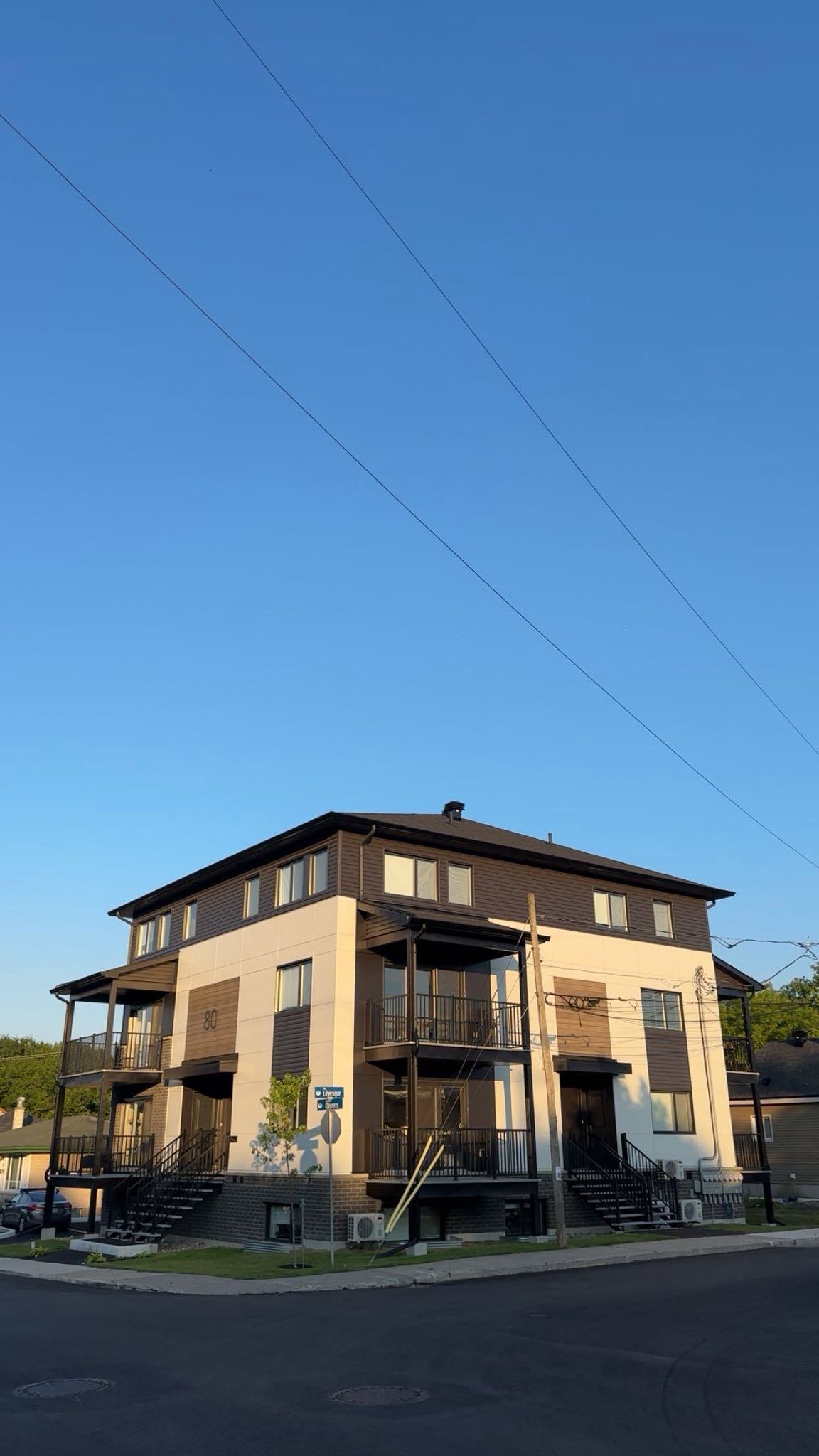 Immeuble d'appartements à plusieurs étages, beige avec des garnitures marron foncé, sous un ciel bleu clair.