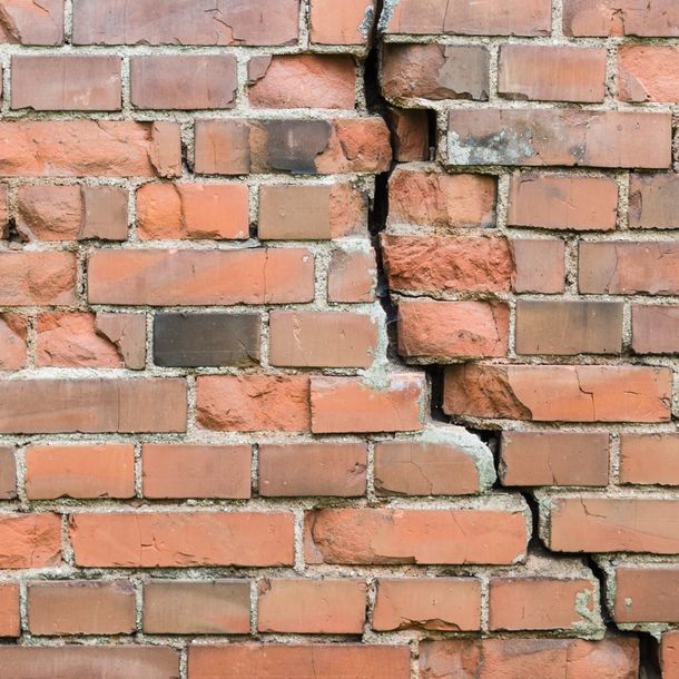 Mur de briques avec une grande fissure verticale.