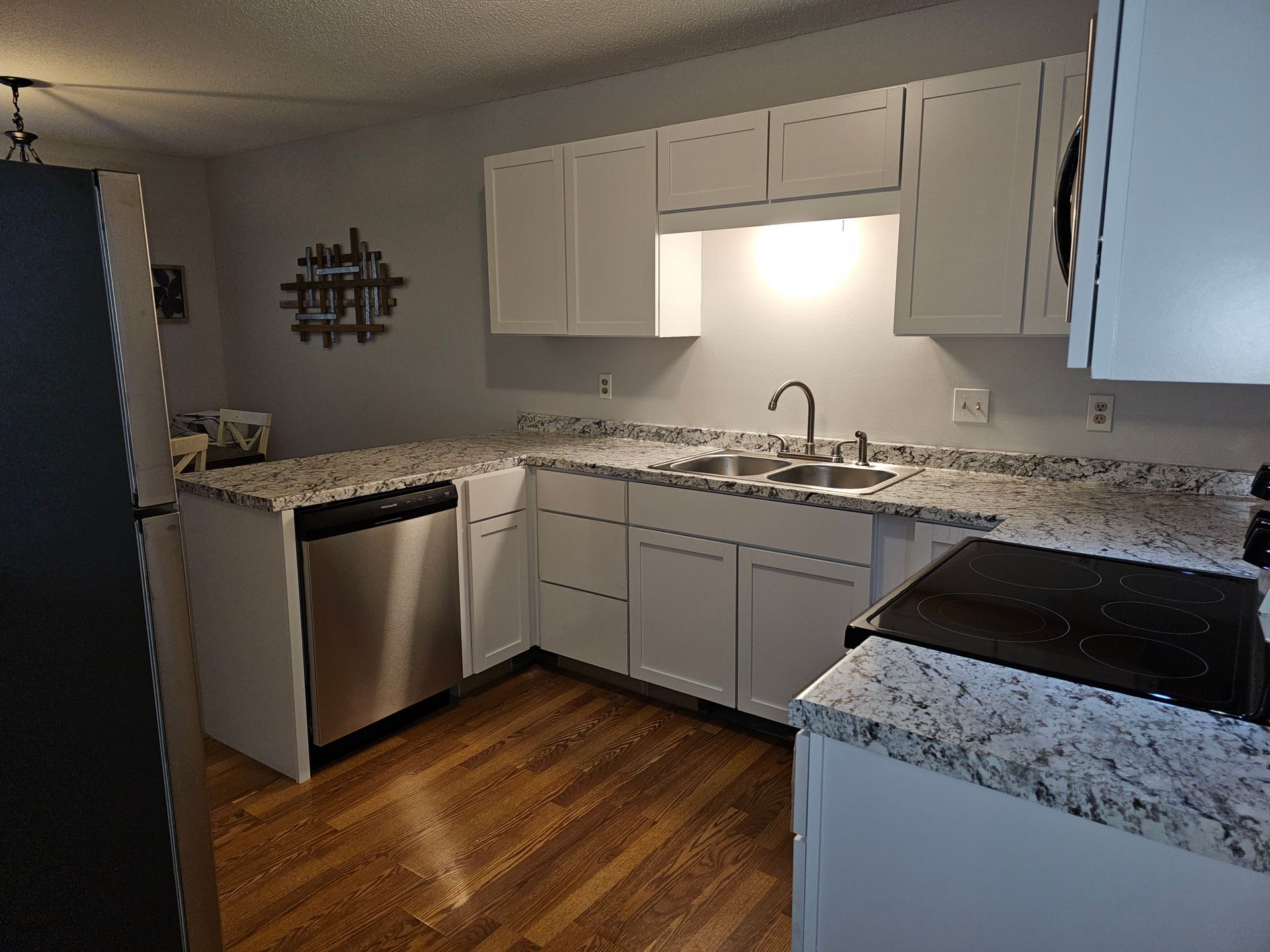 A kitchen with white cabinets , granite counter tops and stainless steel appliances.