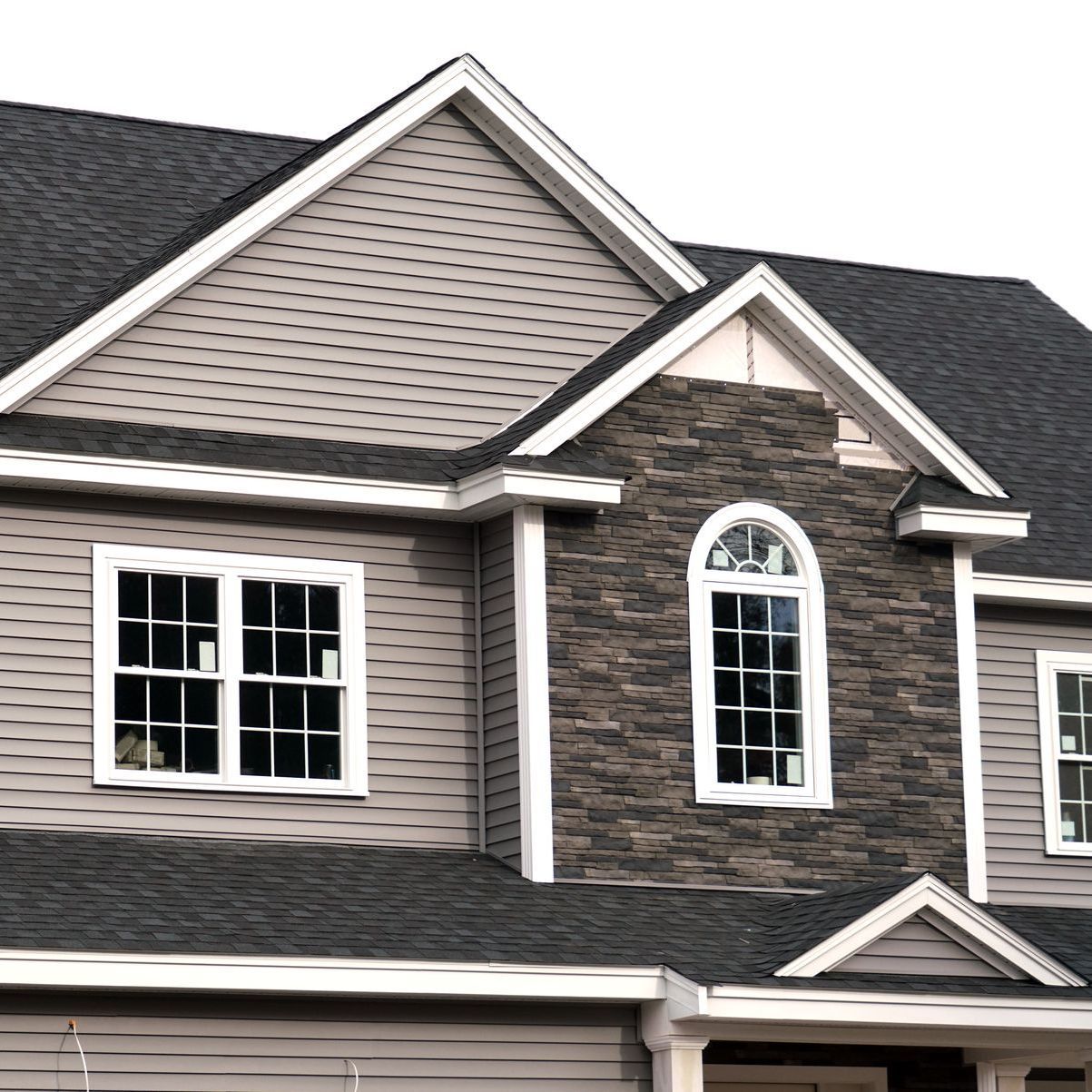 A large house with a gray siding and a black roof