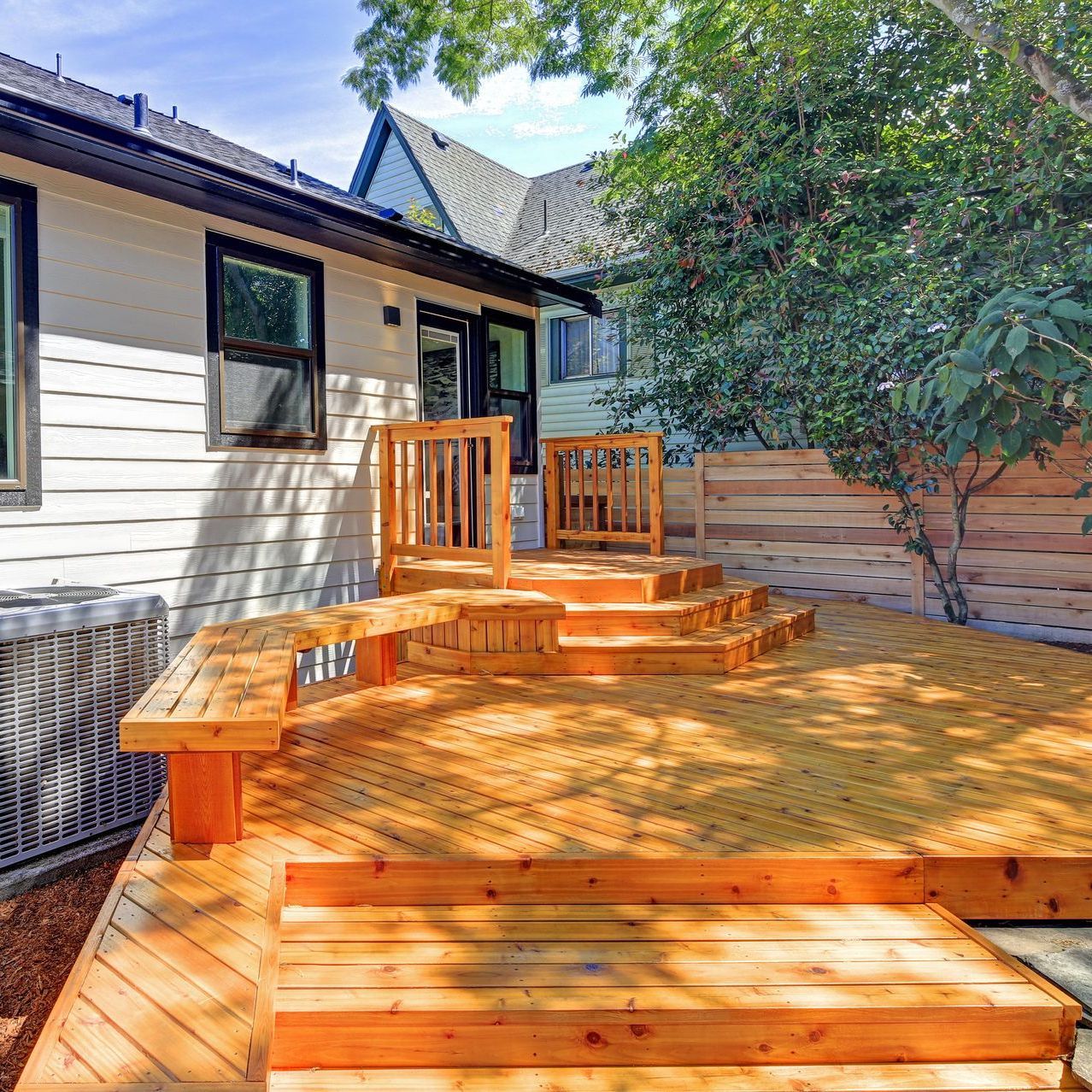 A wooden deck with stairs leading up to it in front of a house.