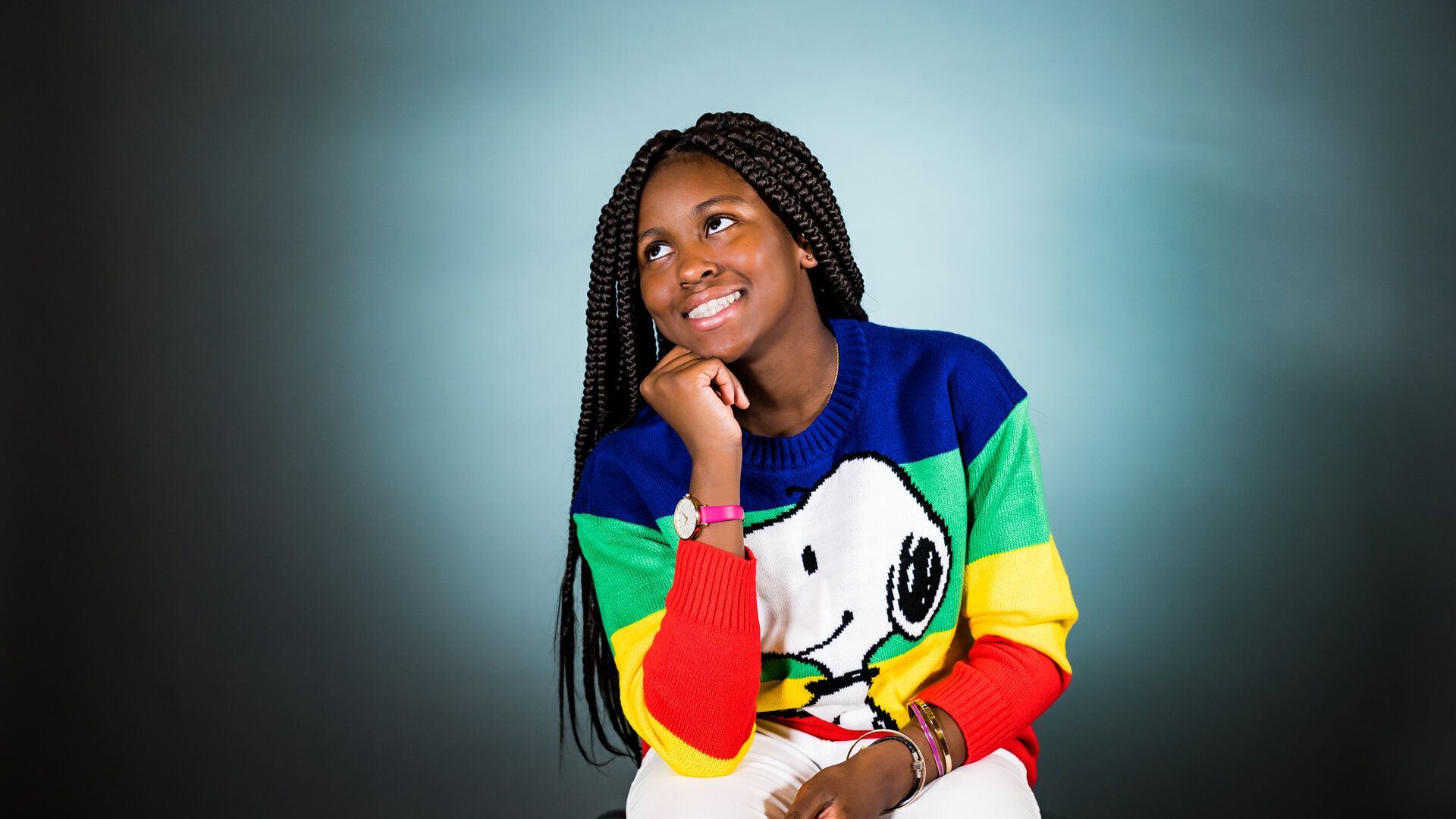 The girl is wearing a snoopy sweater and smiling.