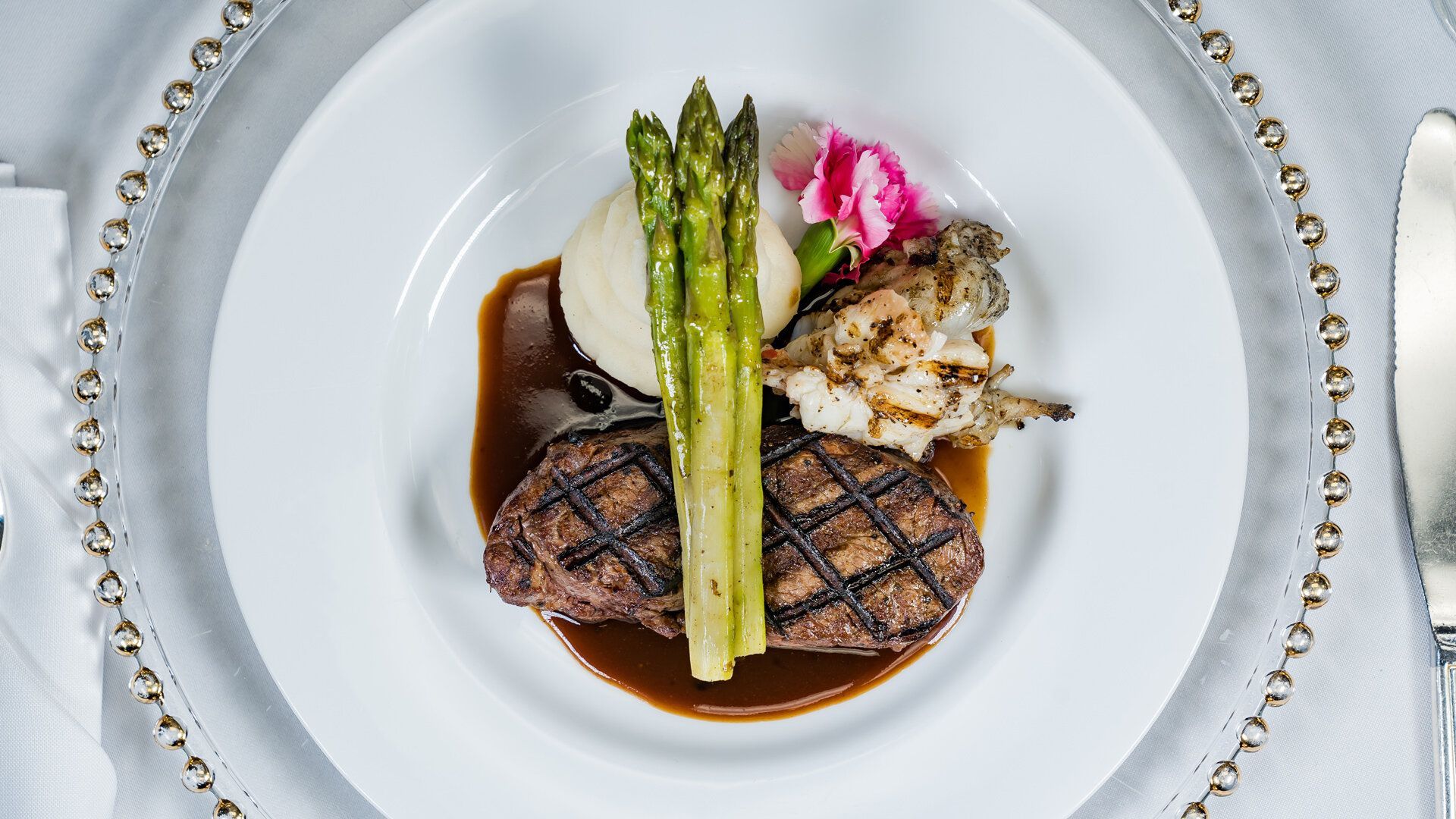 A white plate topped with a steak , asparagus and mashed potatoes.