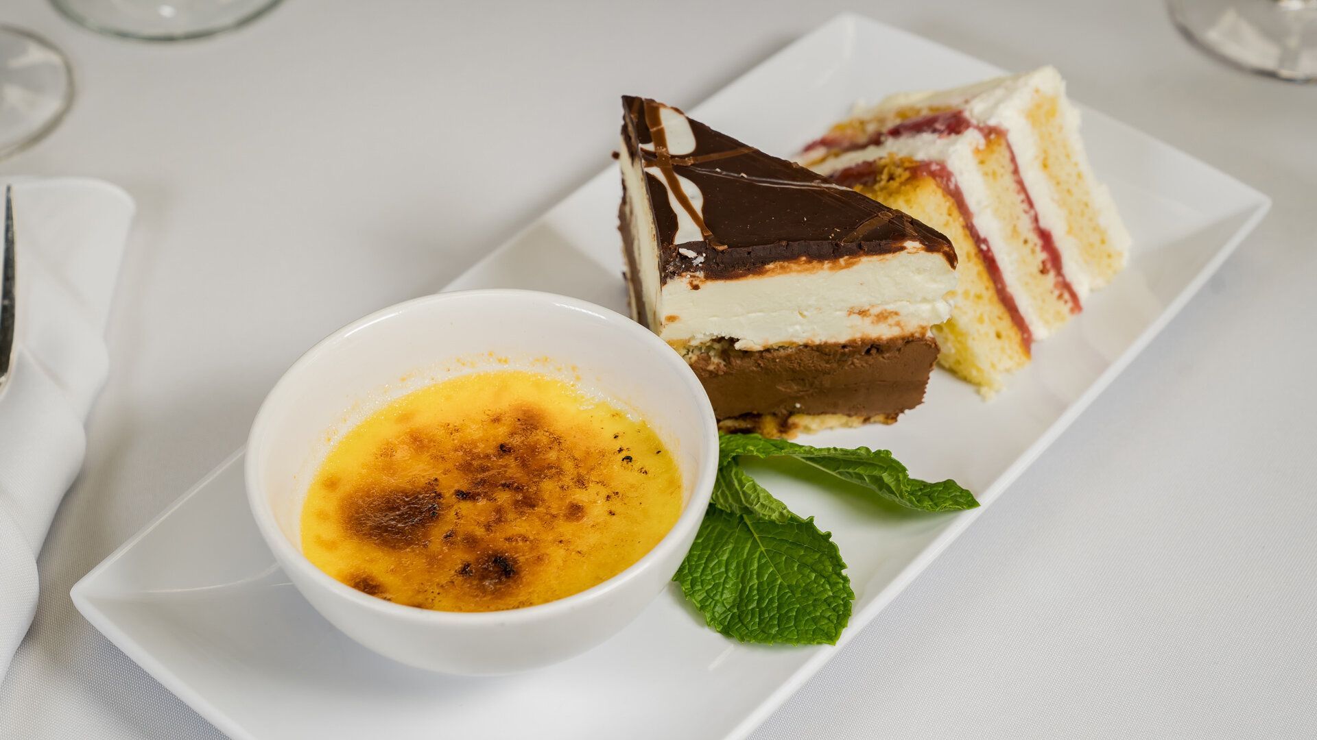 A white plate topped with slices of cake and a bowl of dessert.