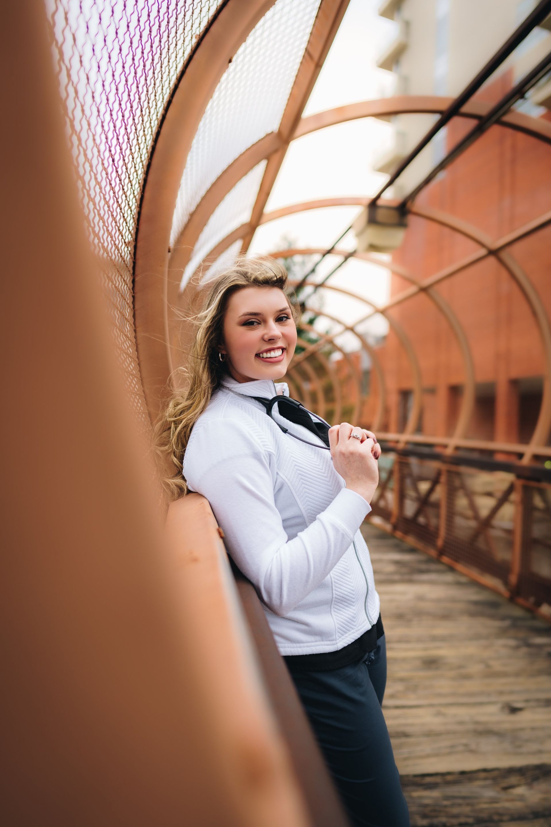 A woman in a white shirt and bow tie is standing on a bridge.