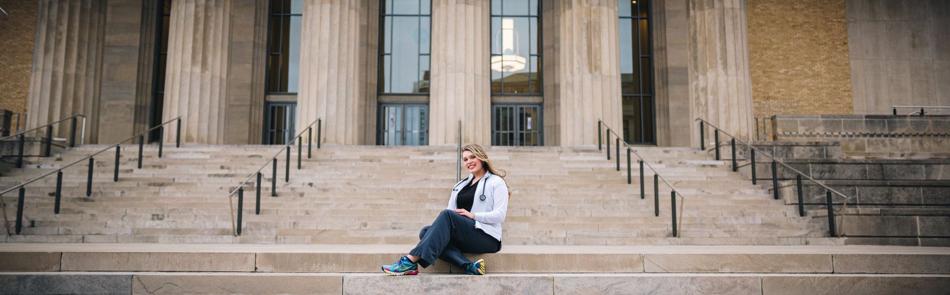 A woman is sitting on the steps of a building.