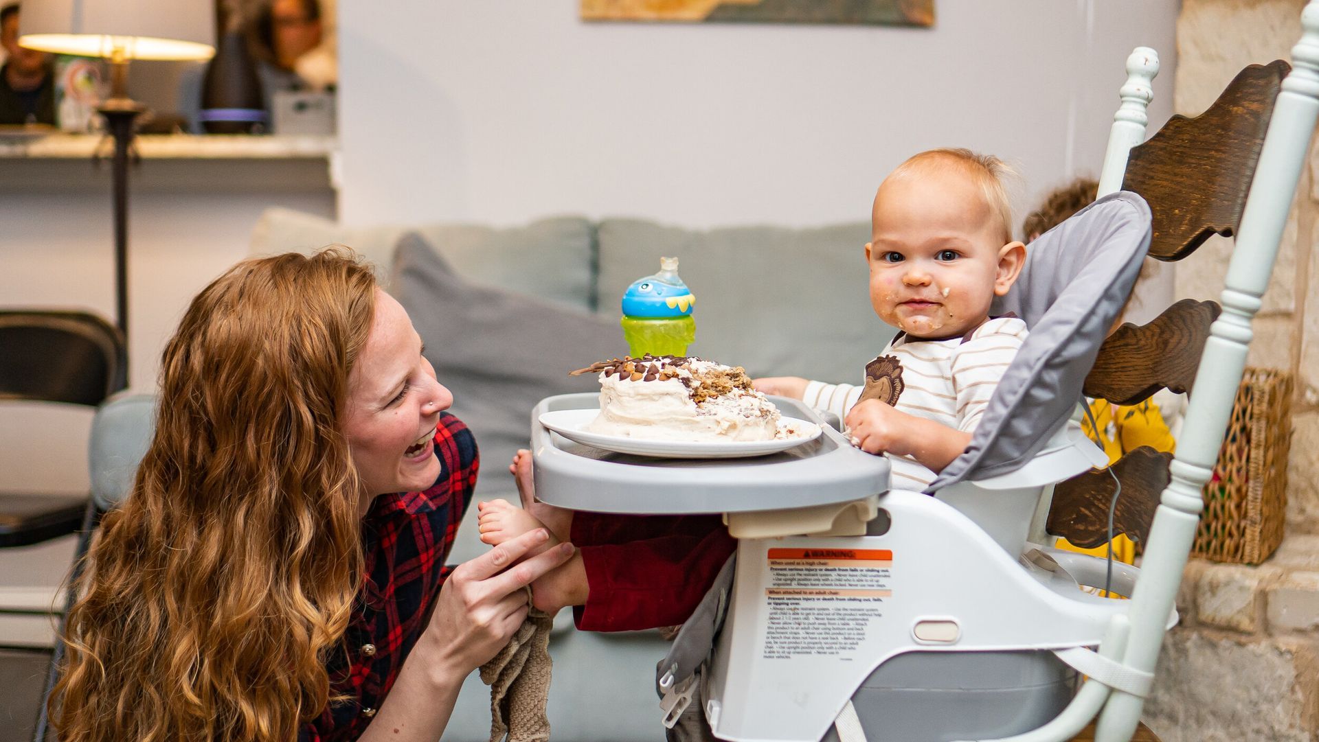 A woman is feeding a baby in a high chair.