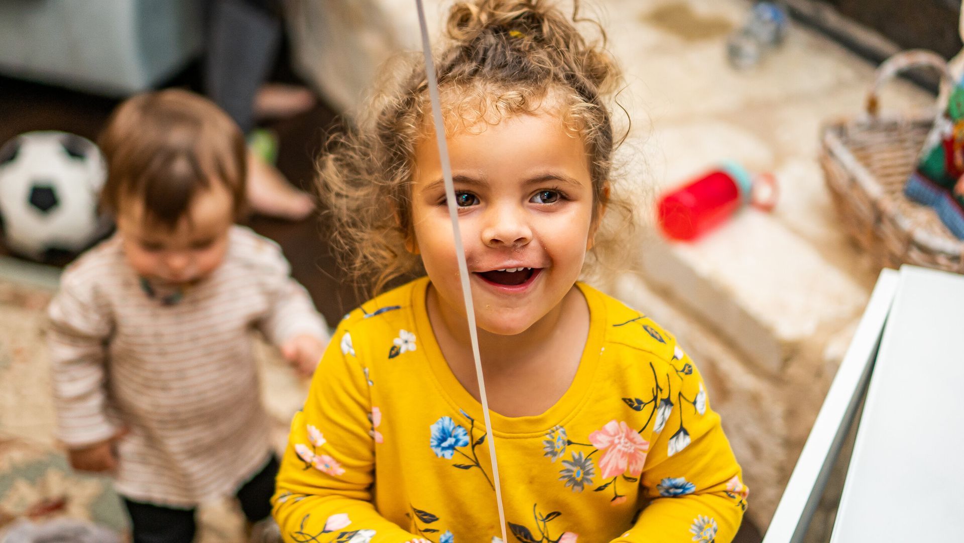 A little girl is playing with a balloon in a living room.
