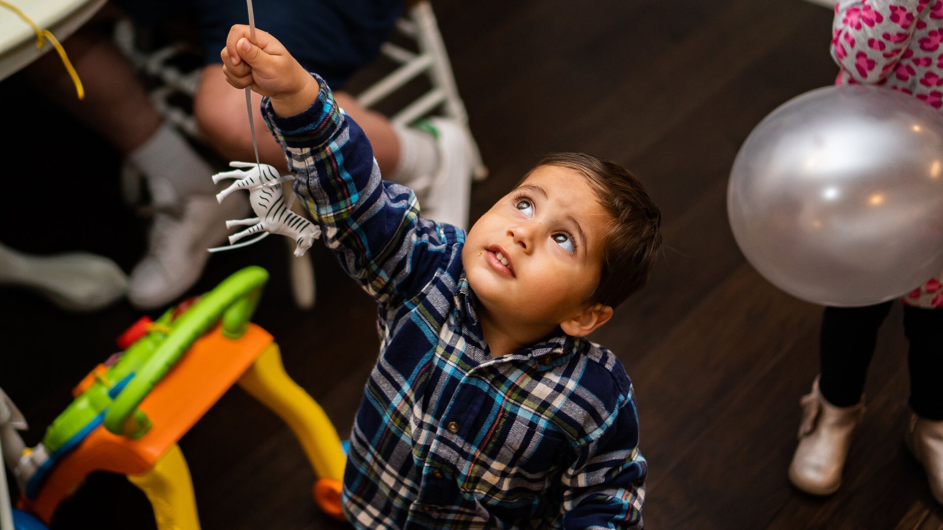 A young boy is holding a balloon and looking up at something.