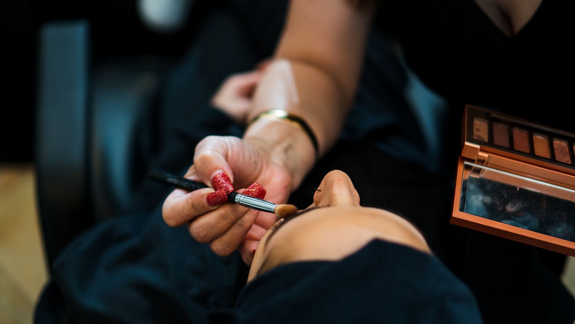 A woman is getting her eye makeup done by a makeup artist.