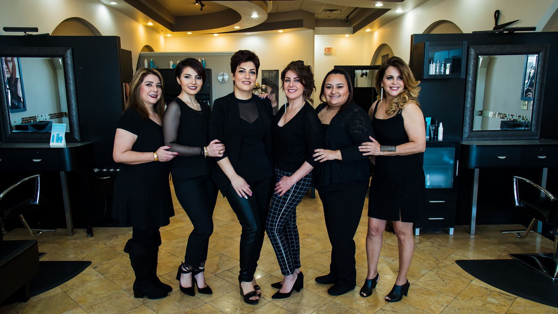 A group of women are posing for a picture in a hair salon.