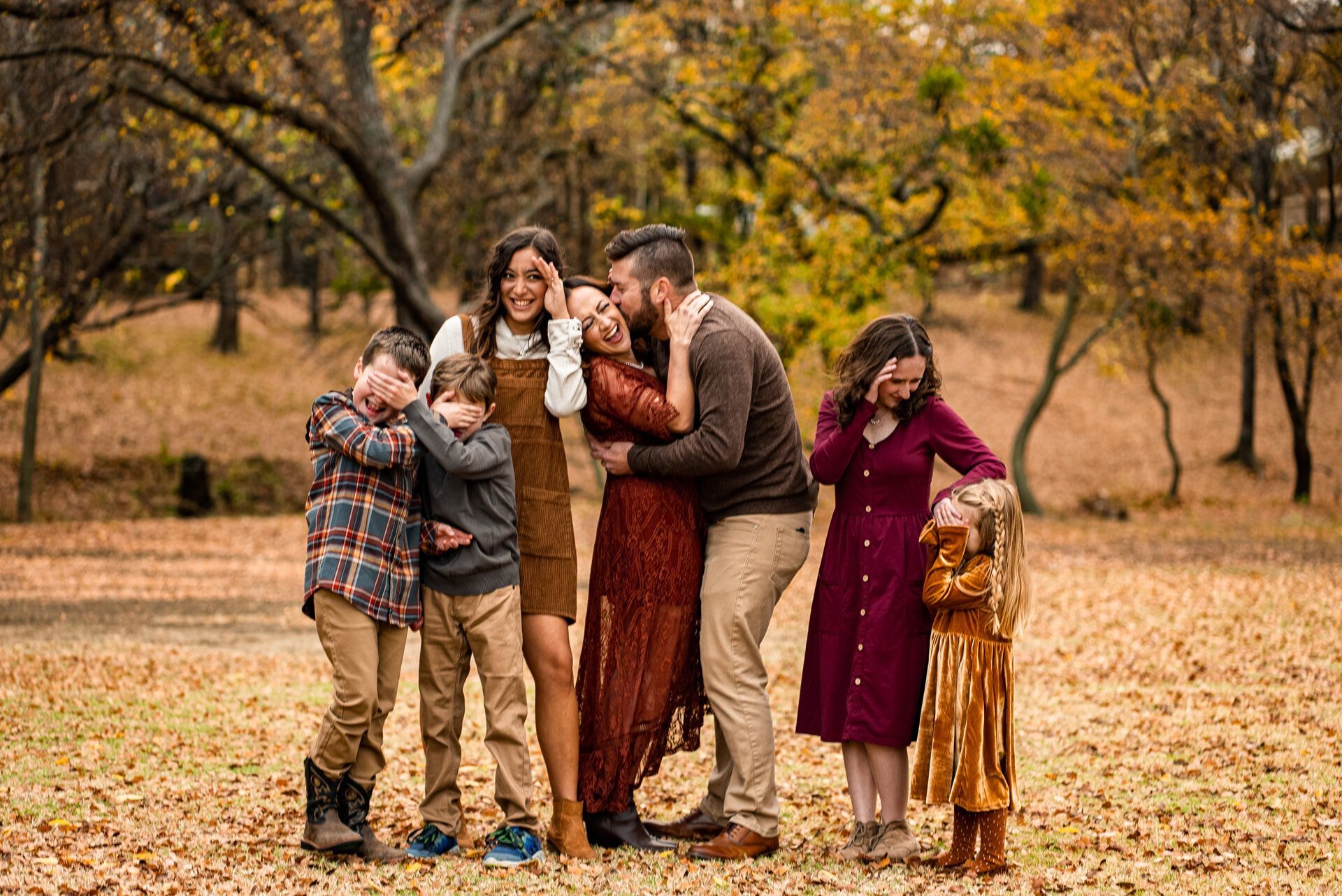 A family is posing for a picture in the woods.