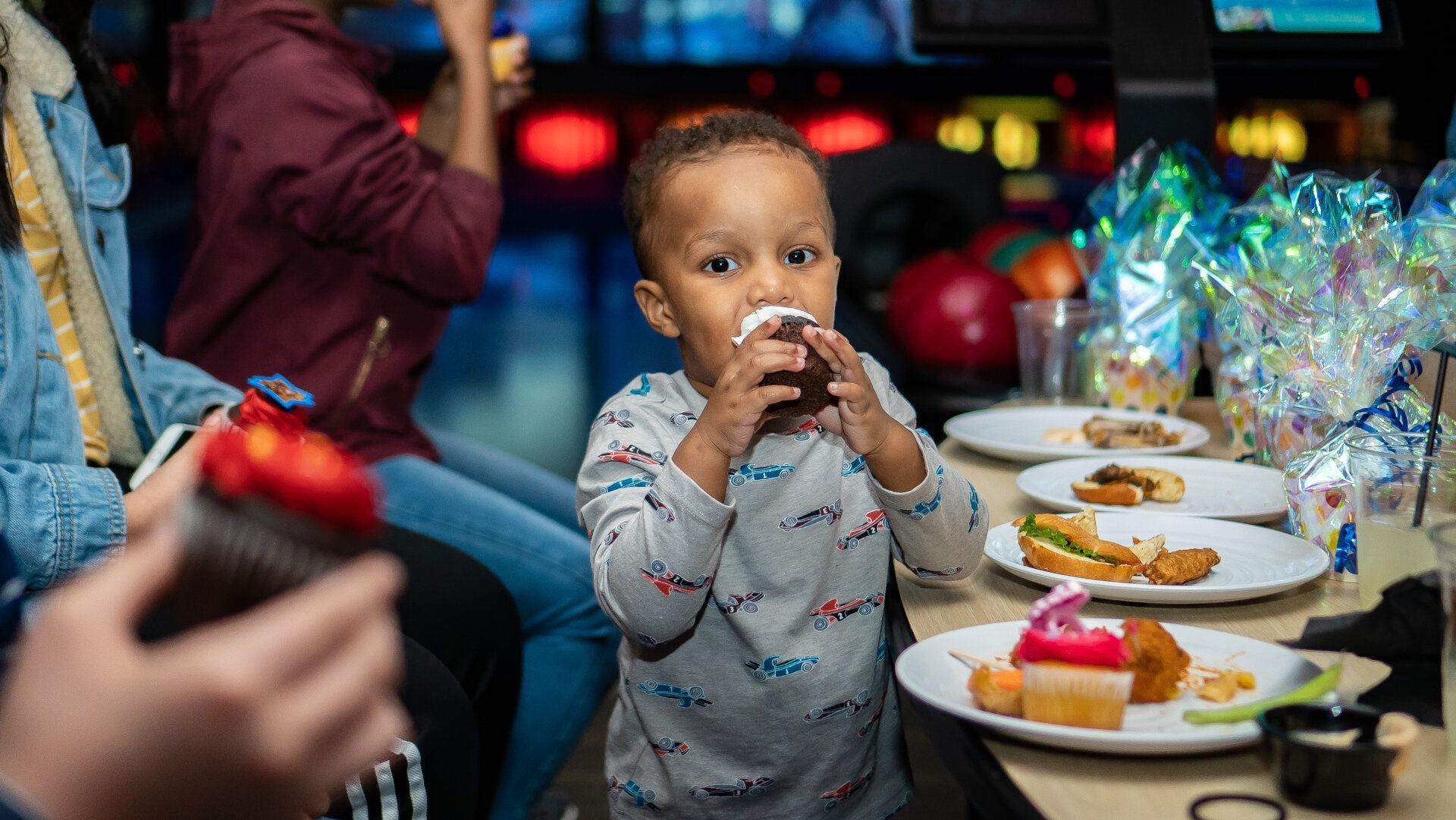 A little boy is eating a cupcake at a birthday party.