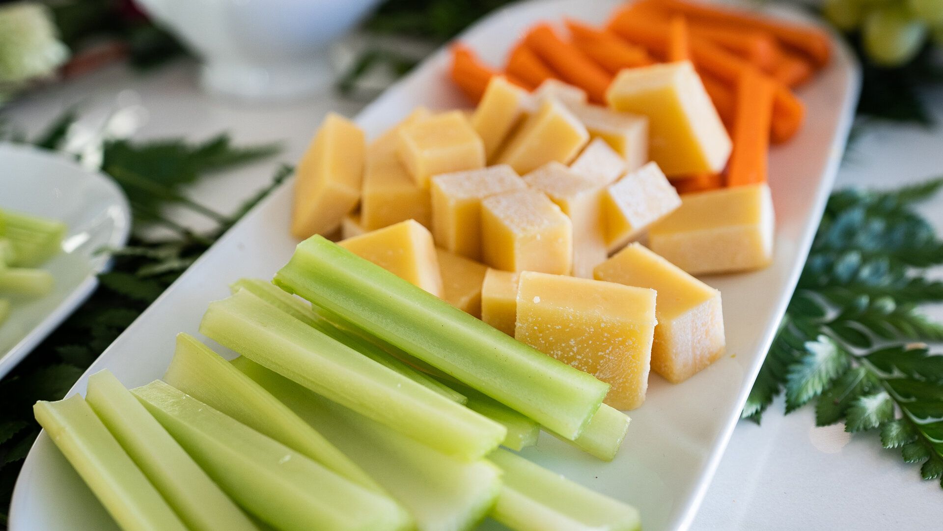 A white plate topped with celery sticks , carrots , and cheese.