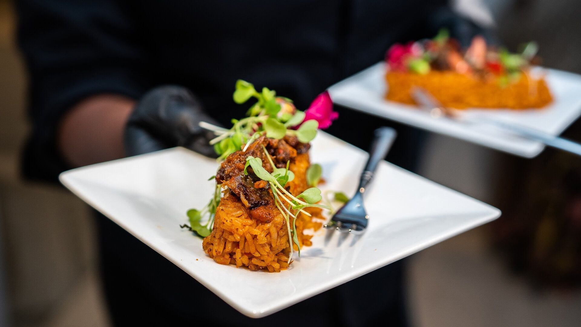 A person is holding a plate of food with a fork.