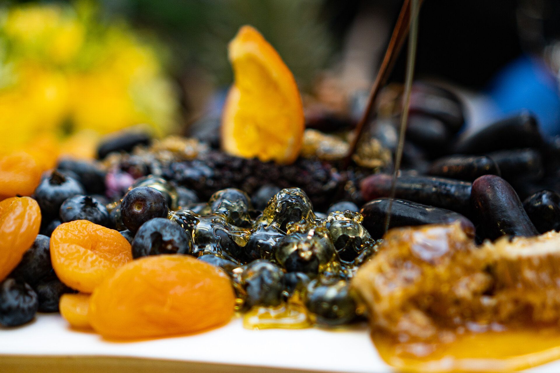 A white plate topped with blueberries , apricots and honey.