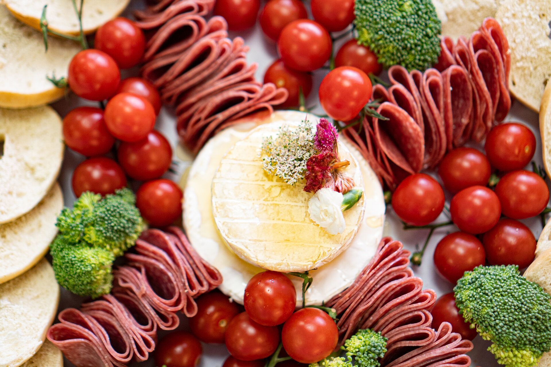 A close up of a plate of food with tomatoes , broccoli , ham and cheese.