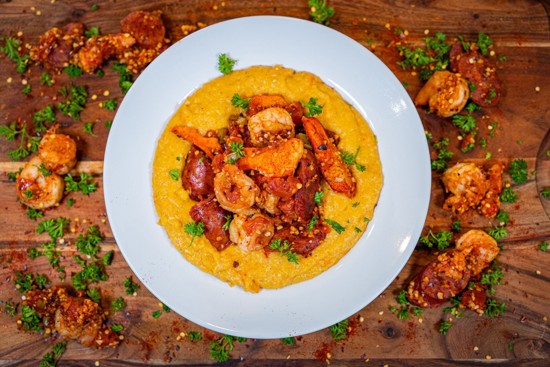 A white plate topped with shrimp and grits on a wooden table.