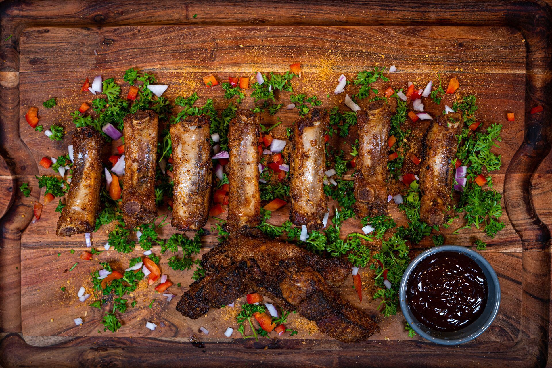 A wooden cutting board topped with food and a bowl of sauce.