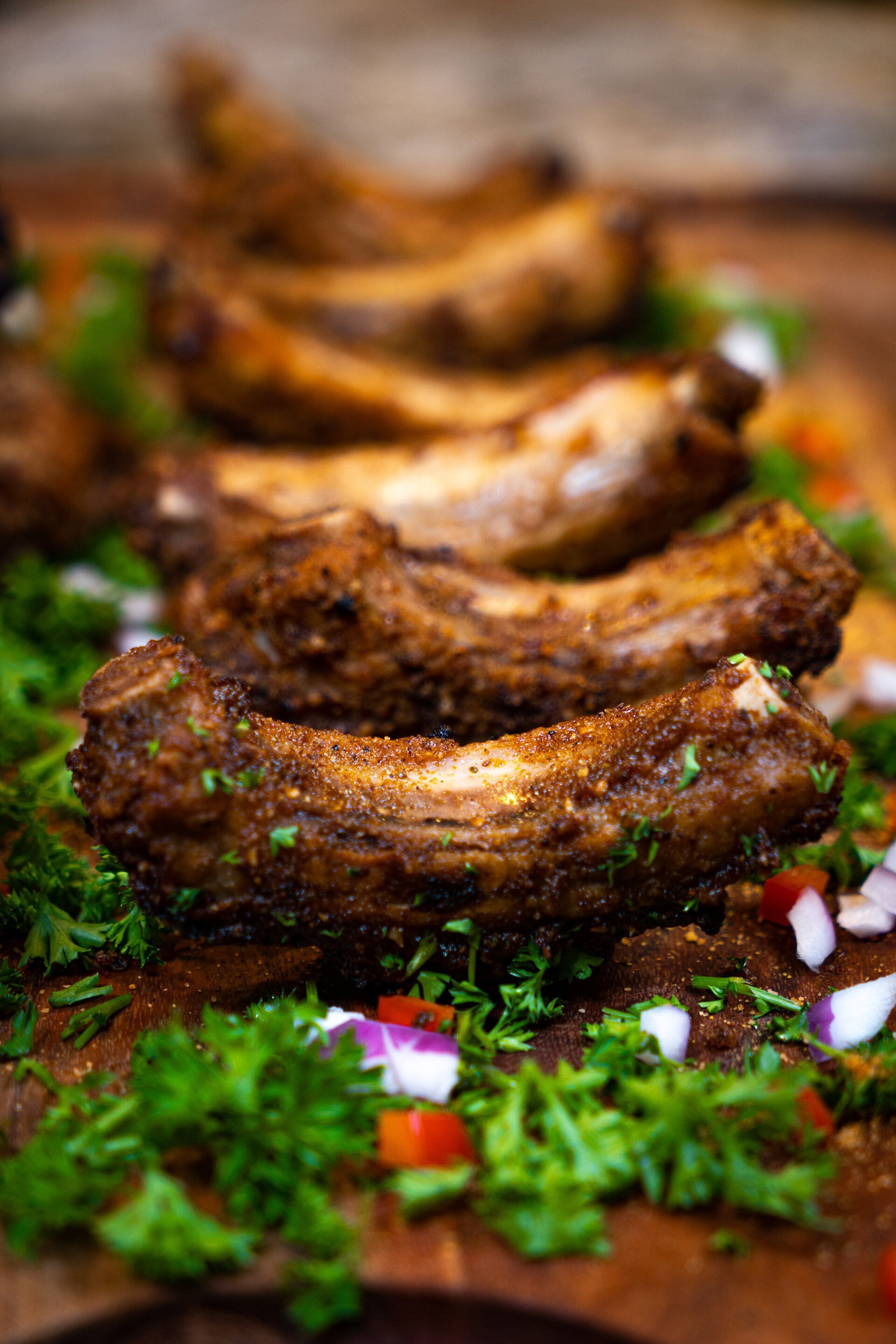 A row of ribs sitting on top of a wooden cutting board.