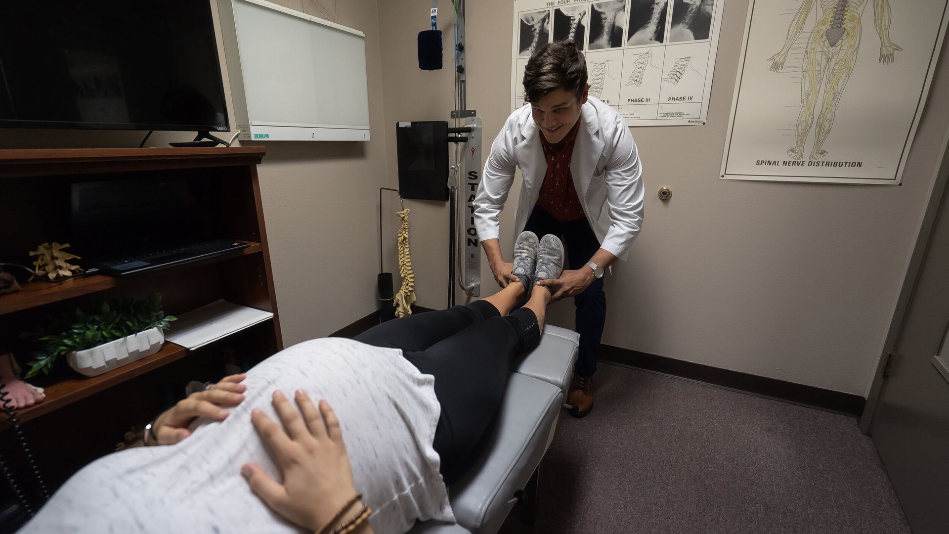 A woman is laying on a table while a doctor examines her foot.