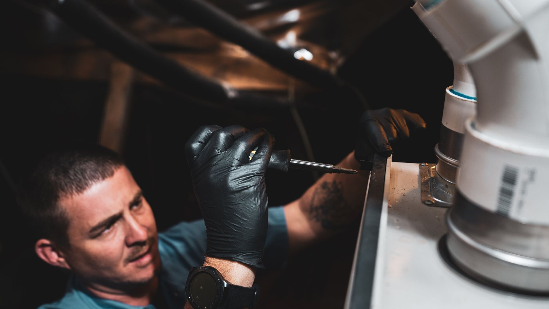 A man is working on a pipe with a drill.