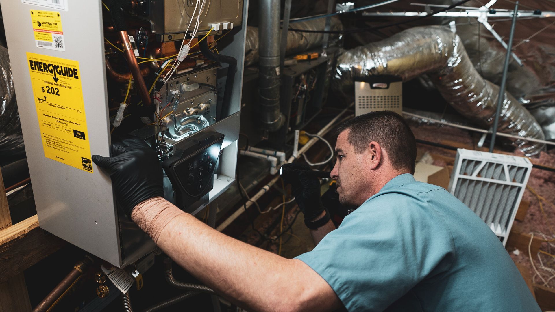A man is working on an air conditioner in a basement.