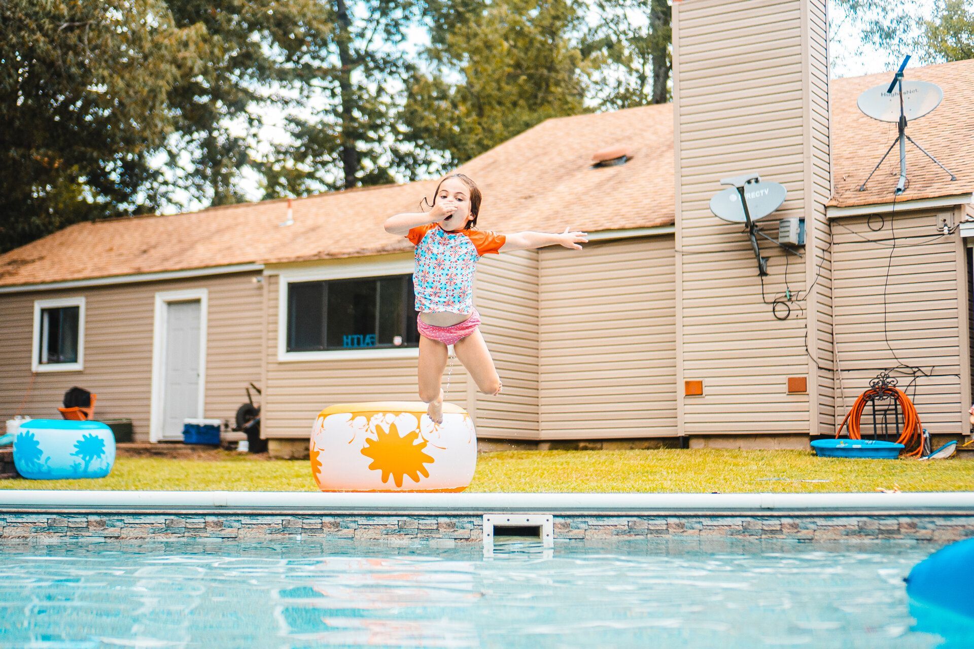 A little girl is jumping into a swimming pool.