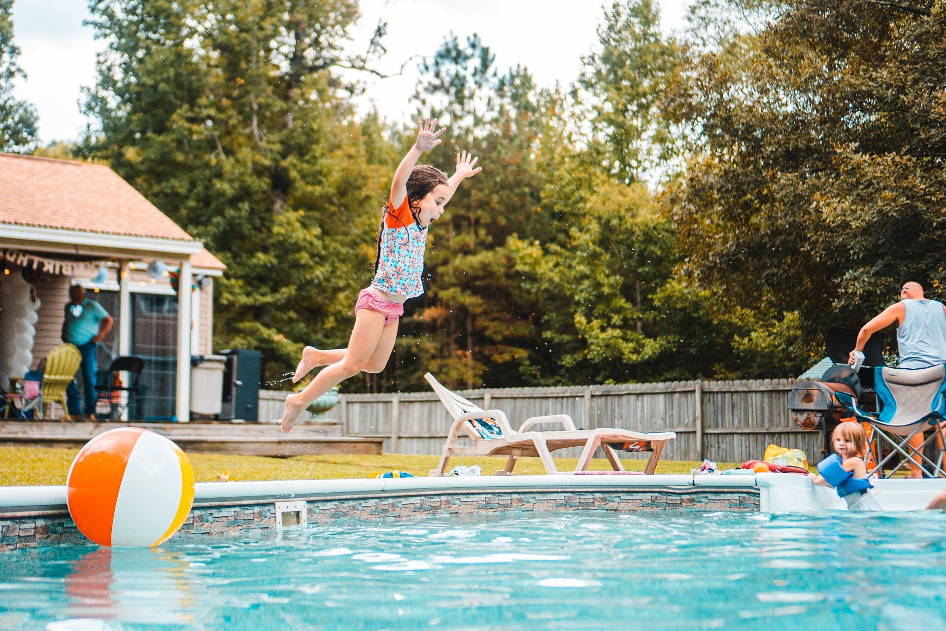 A girl is jumping into a swimming pool.