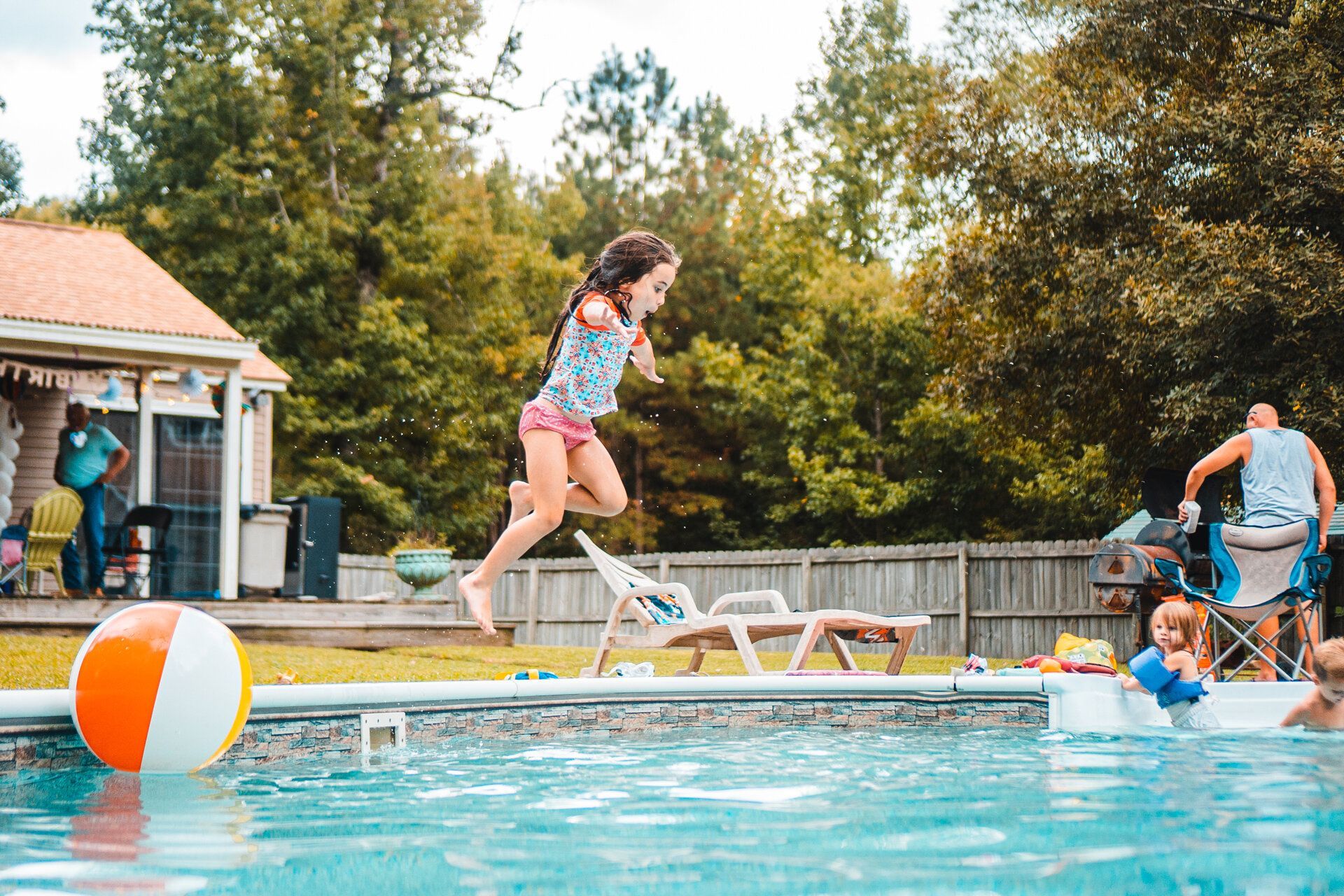 A little girl is jumping into a swimming pool.