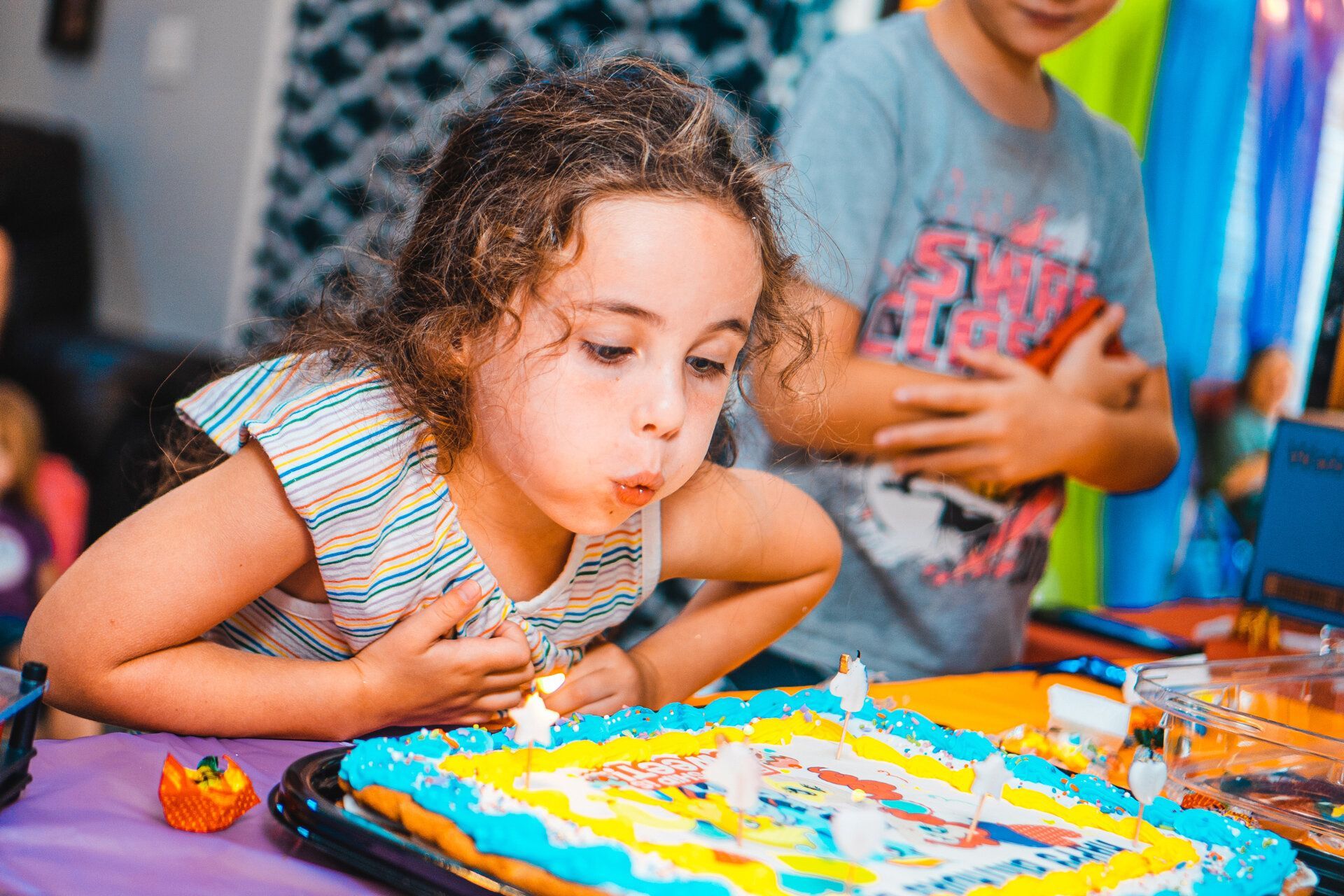 A little girl is blowing out candles on a birthday cake.